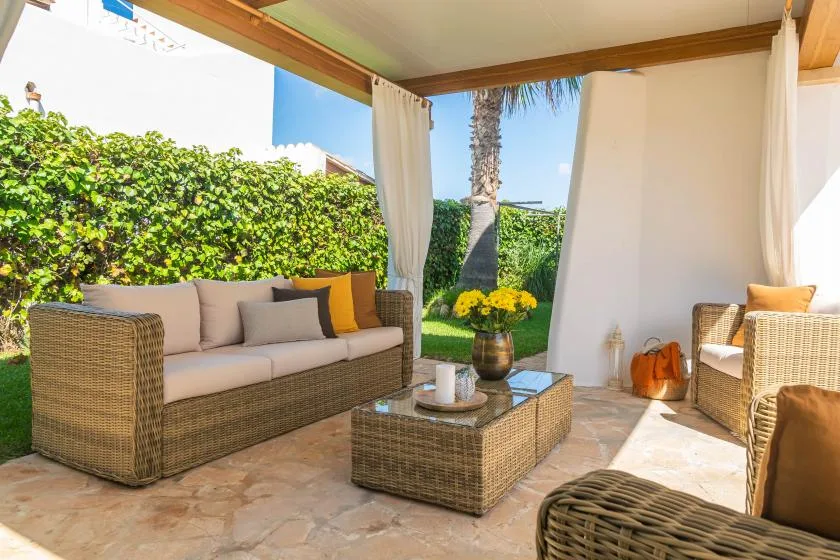 A covered outdoor seating area with wicker furniture and a glass-topped table.
