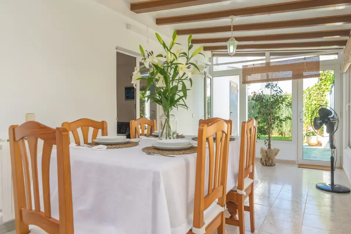 A dining area with a set table and glass doors opening onto greenery.