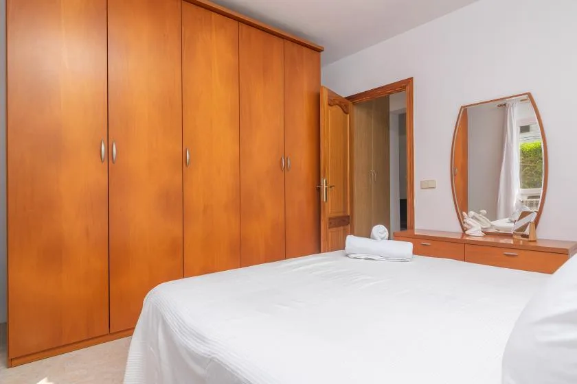 A bedroom with a neatly made bed, wooden wardrobes, and a mirror.