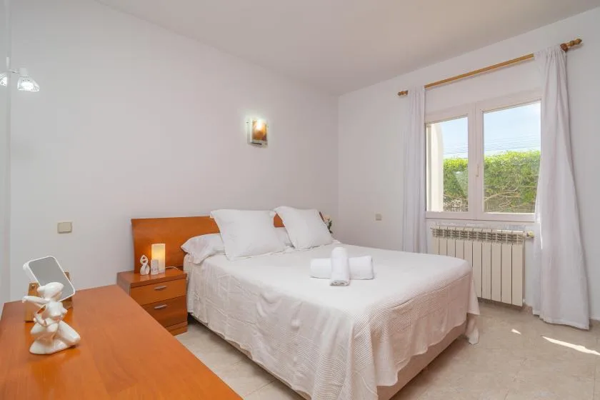 A bedroom with a double bed beside a window.