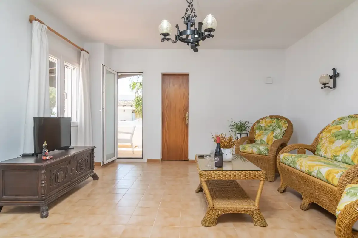 A bright living room with wicker seating and a glass-topped coffee table.