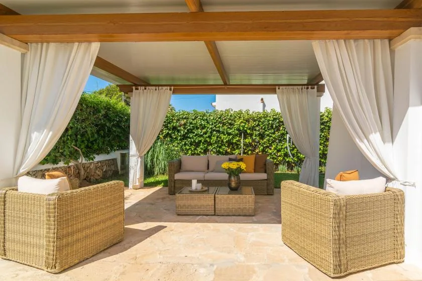 A covered outdoor seating area with curtains and a low table.
