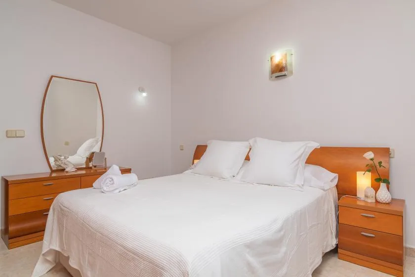 A bedroom with a neatly made bed, bedside tables, and a dressing mirror.