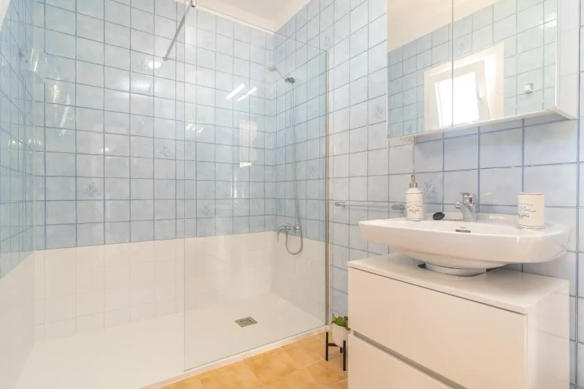 A tiled bathroom with a walk-in shower and a sink vanity.