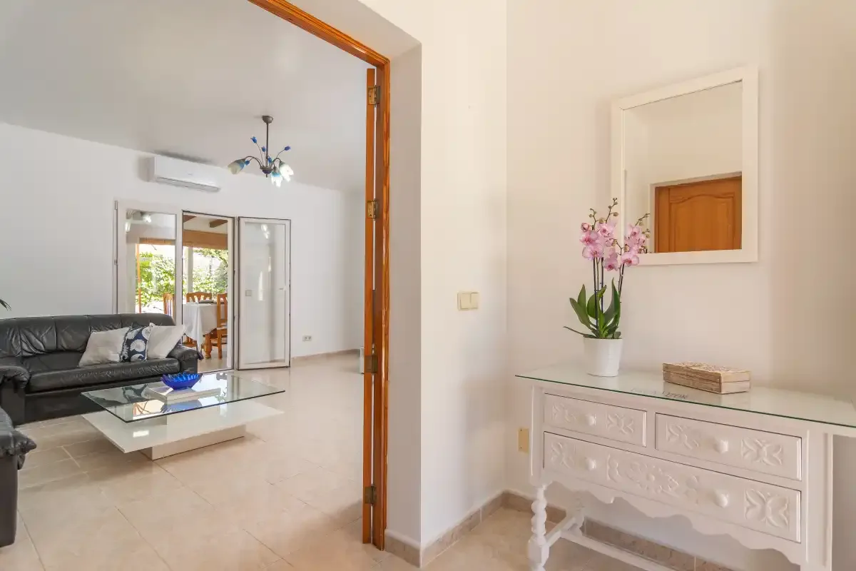 A bright living room with seating and a glass coffee table beside a console.