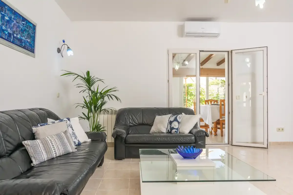 A bright living room with dark seating and a glass coffee table.