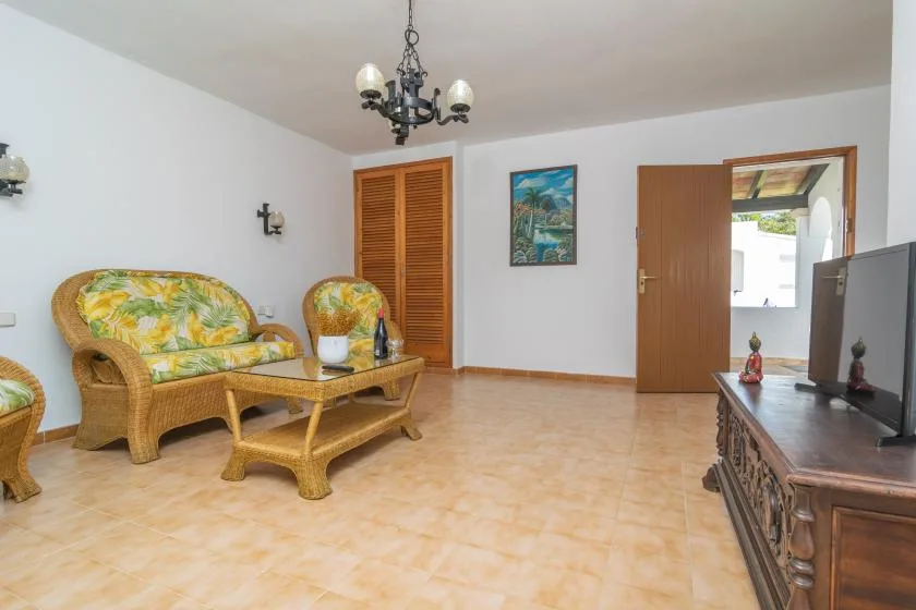A living room with wicker seating, a low table, and a television.