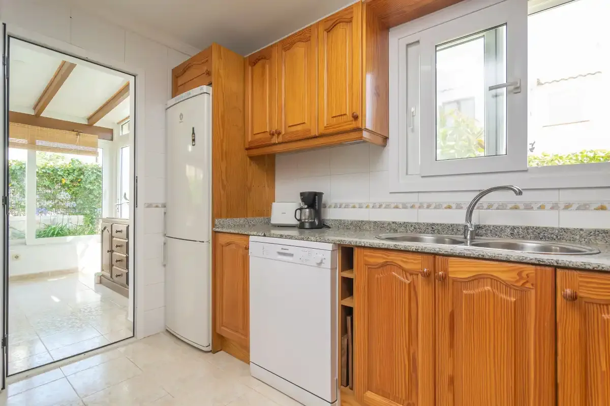 A bright kitchen with wooden cabinets and a sink beneath the window.
