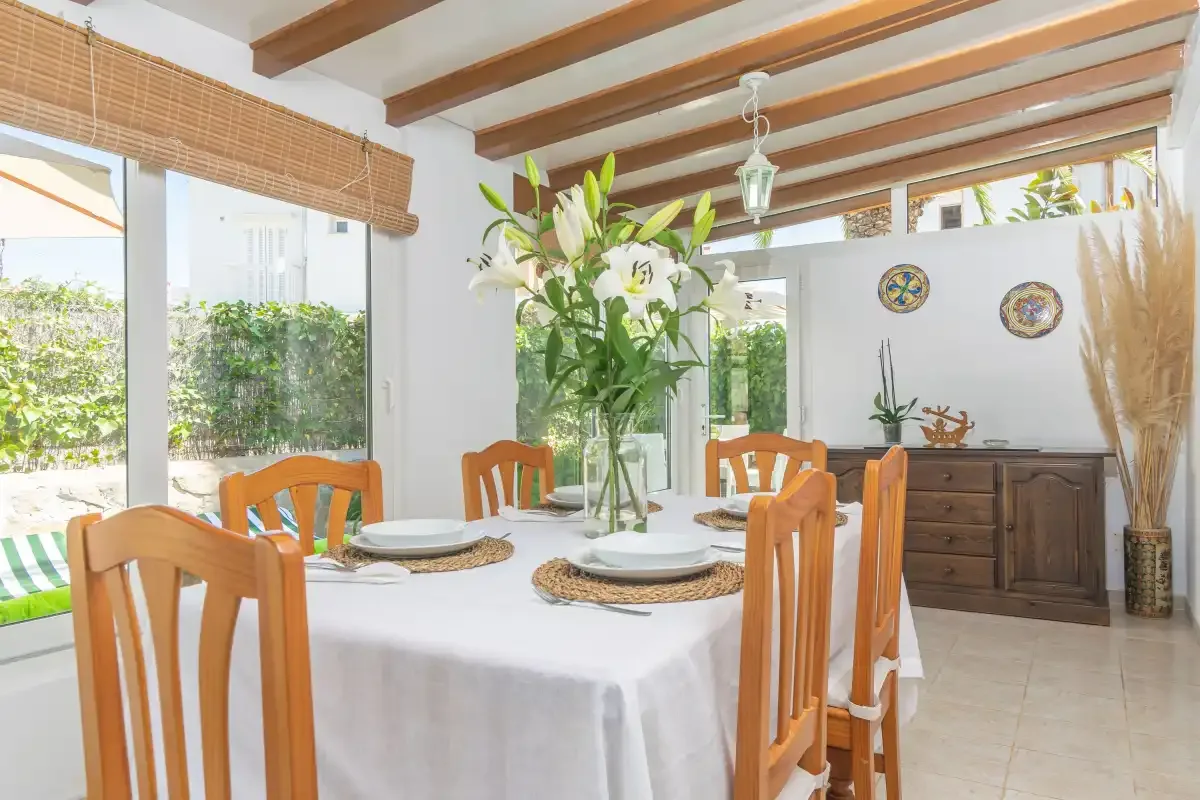 A bright dining room with a table set with plates and flowers.