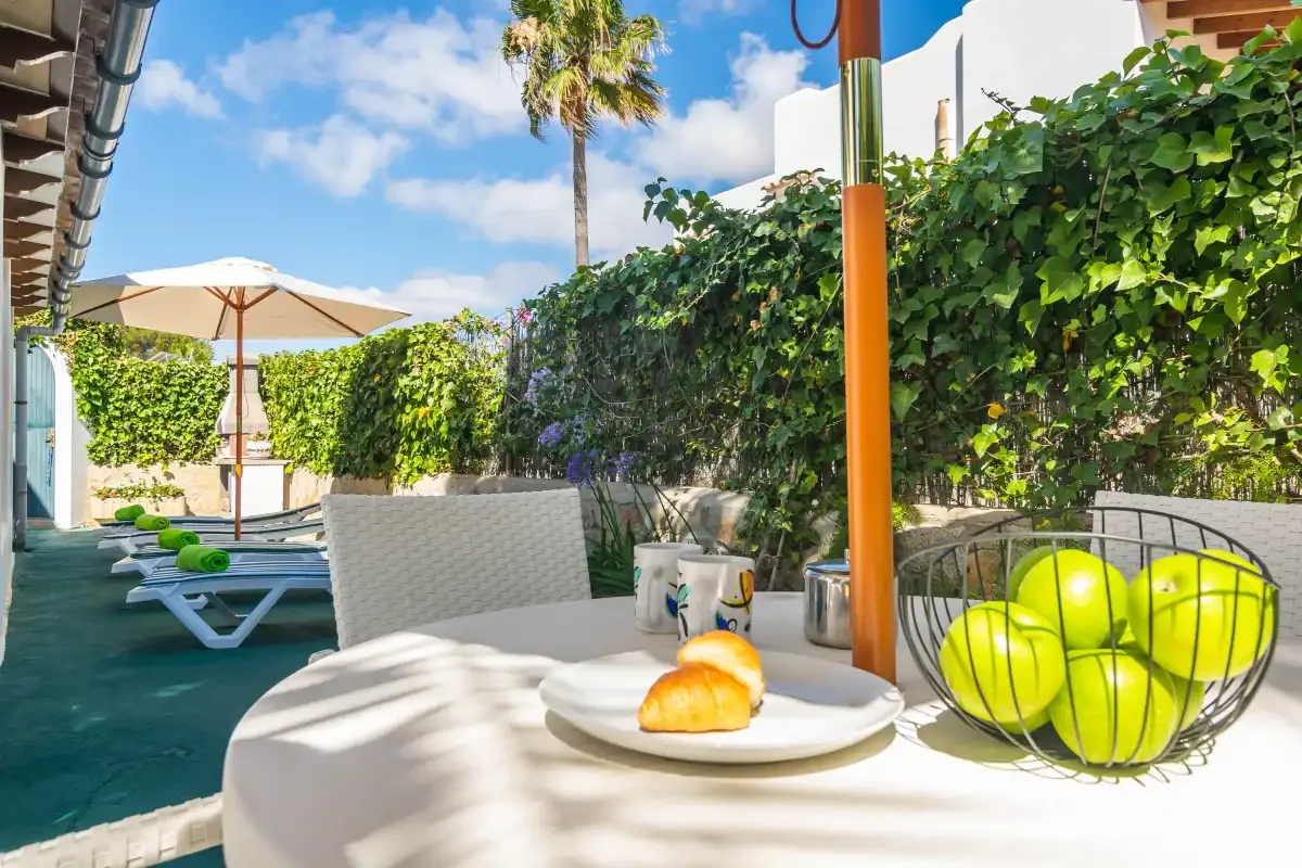 An outdoor patio dining area with a table, seating, and greenery.