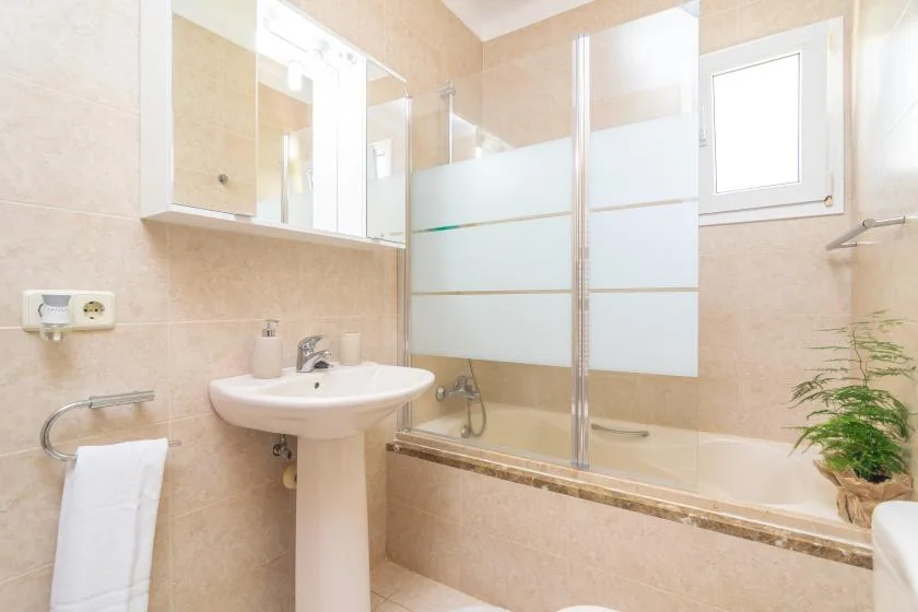 A bright bathroom with a sink, bathtub, and frosted glass panels.