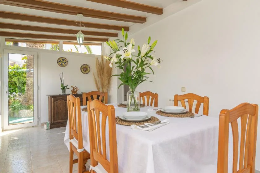 A dining room with a set table and a vase of flowers.