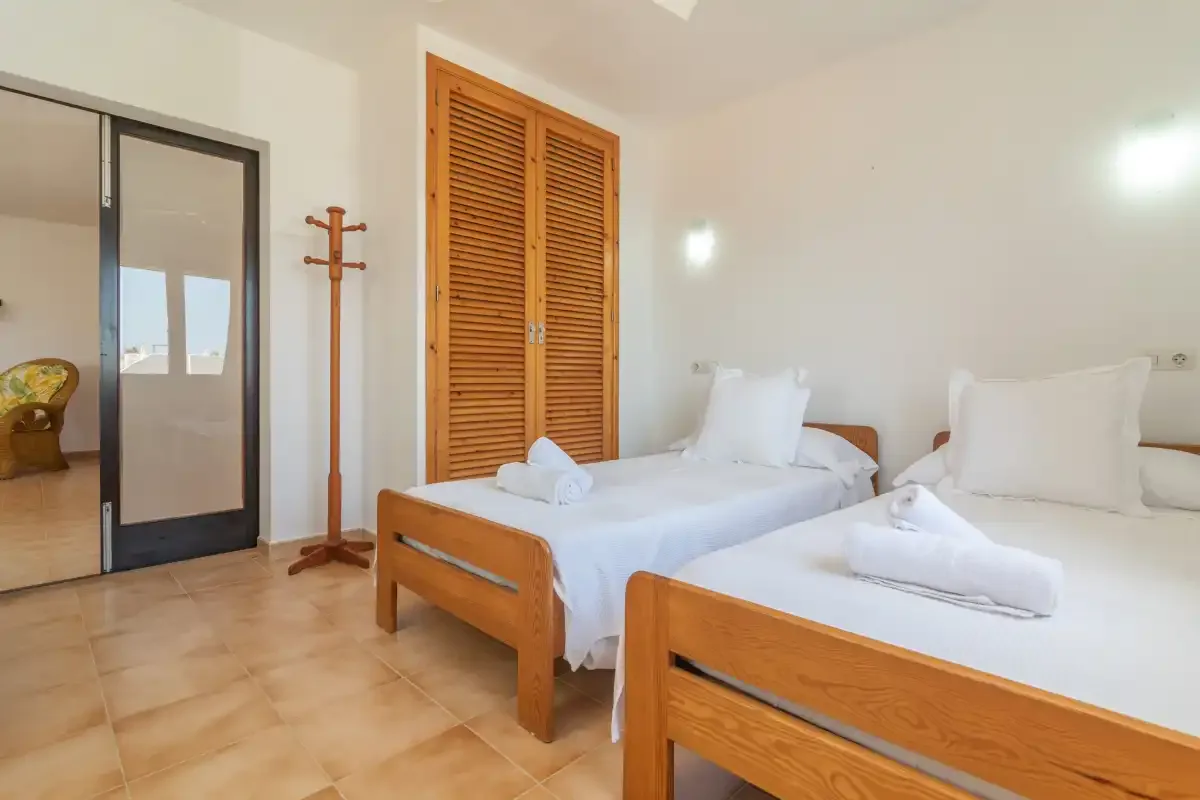A bedroom with two single beds and wooden louvered closet doors.