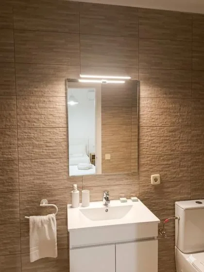 A bathroom vanity with a sink, mirror, and towel against tiled walls.