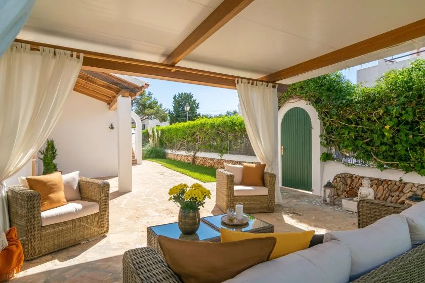 A covered patio with wicker seating and an open view of the garden.