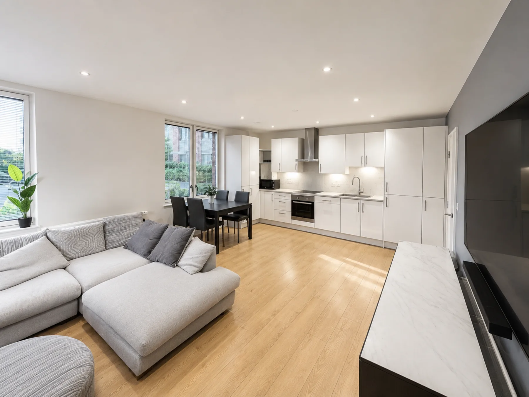 A bright open-plan living area with seating, a dining table, and a kitchen.