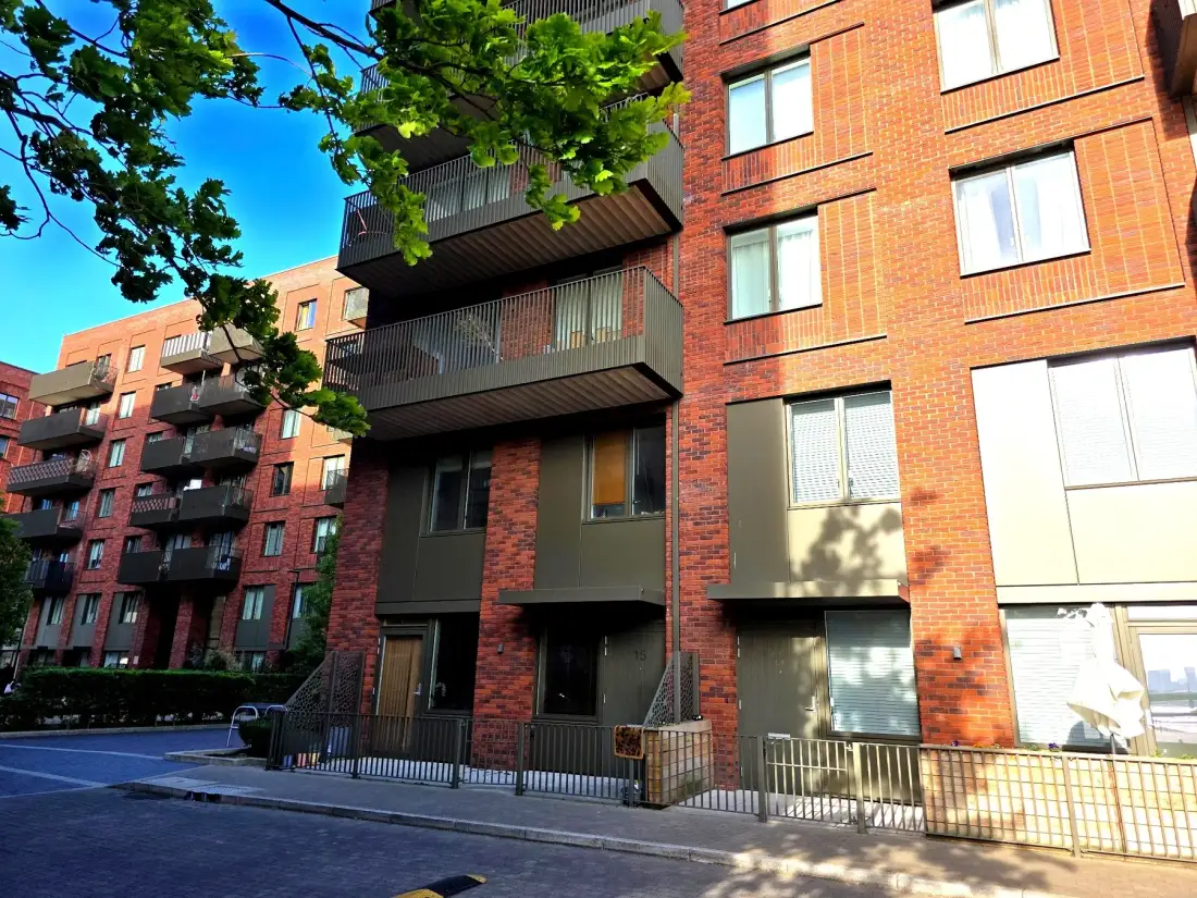 A brick apartment building with balconies and windows along the street.