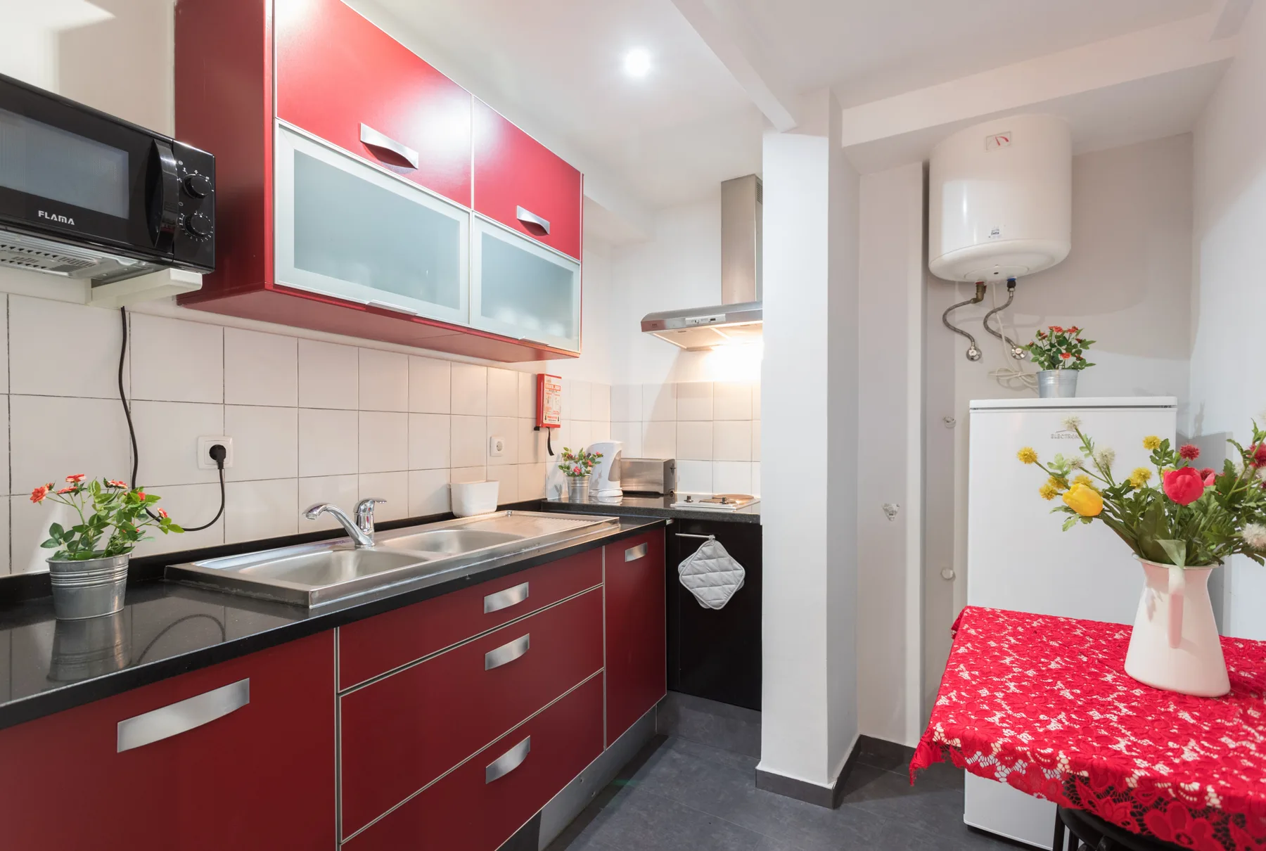 A red-and-white kitchen with a black countertop and a small dining table.
