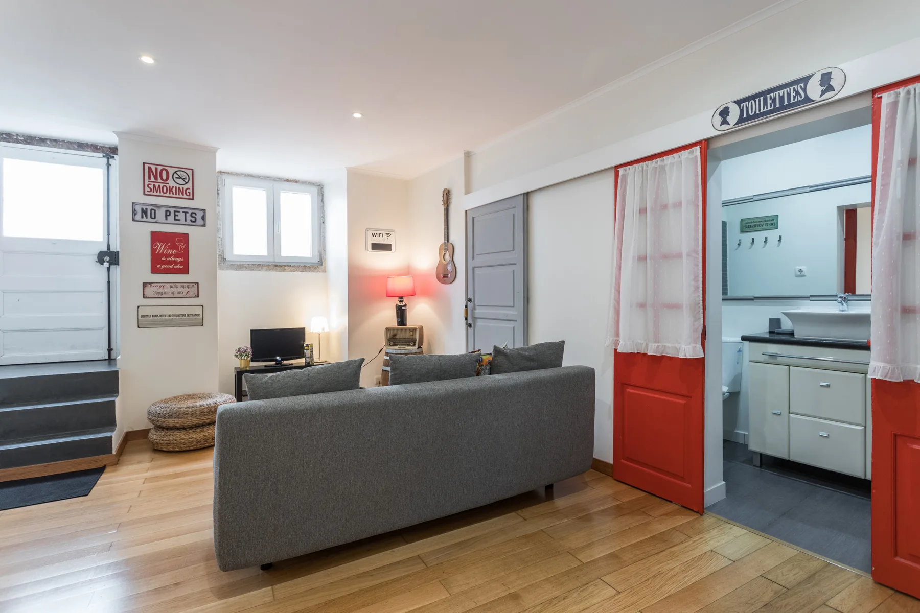 A living room with gray seating and a doorway opening onto a bathroom.