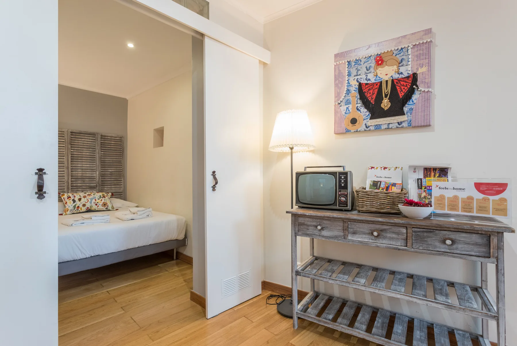 A bedroom with a bed and a rustic console table holding a small television.