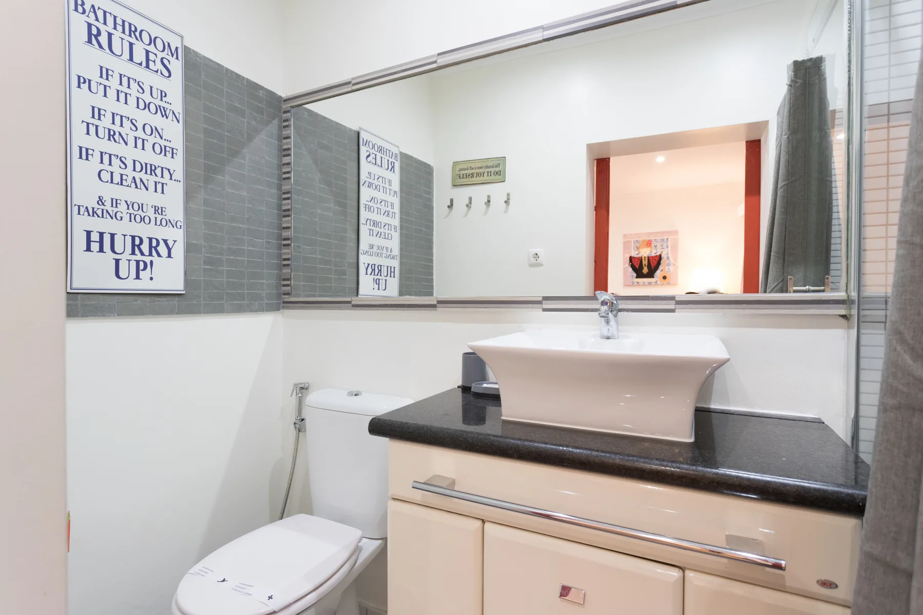 A bathroom with a sink, toilet, and large wall mirror.