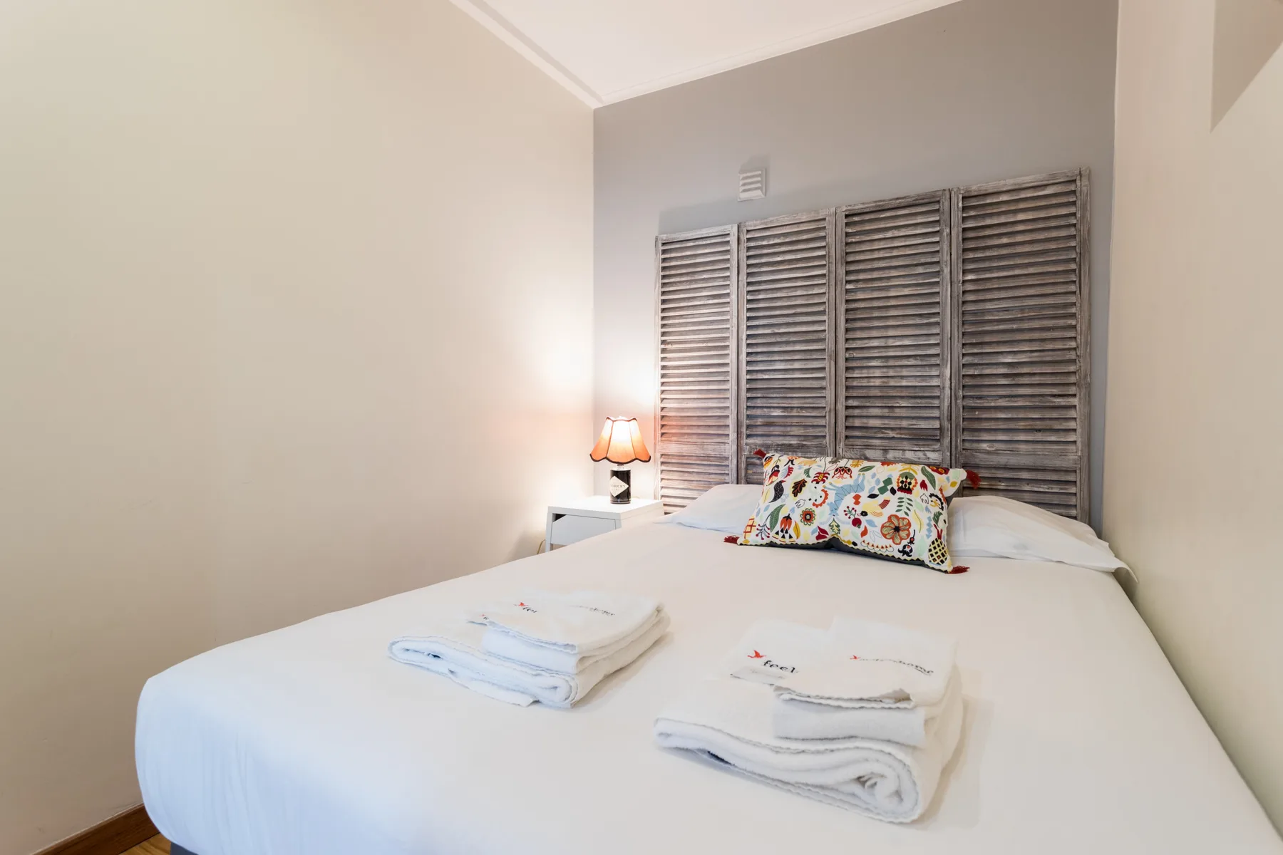A bedroom with a neatly made bed and folded towels.