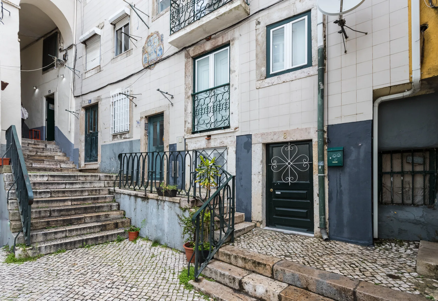 A tiled entrance courtyard with stone steps and a dark green door.