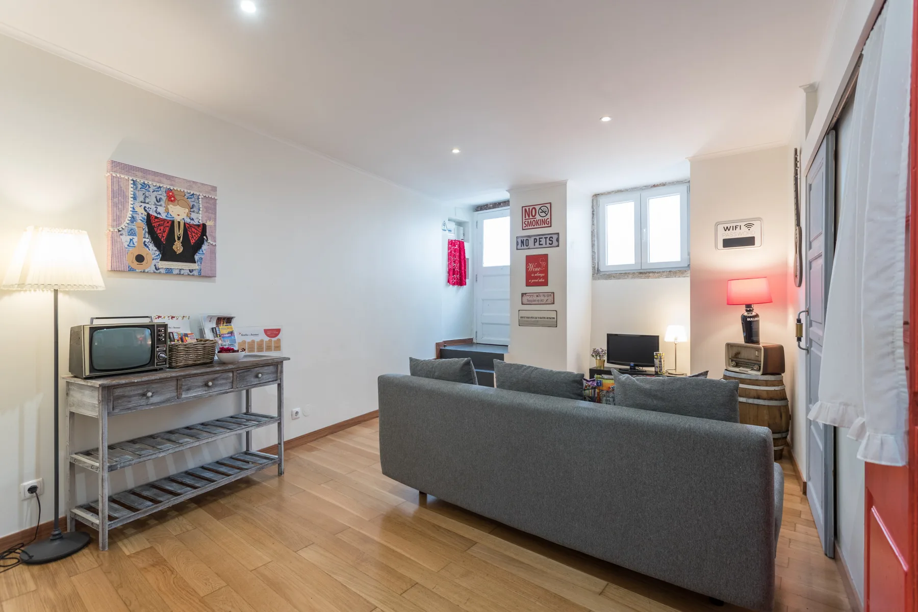 Living room with gray seating, a television, and a wooden floor.