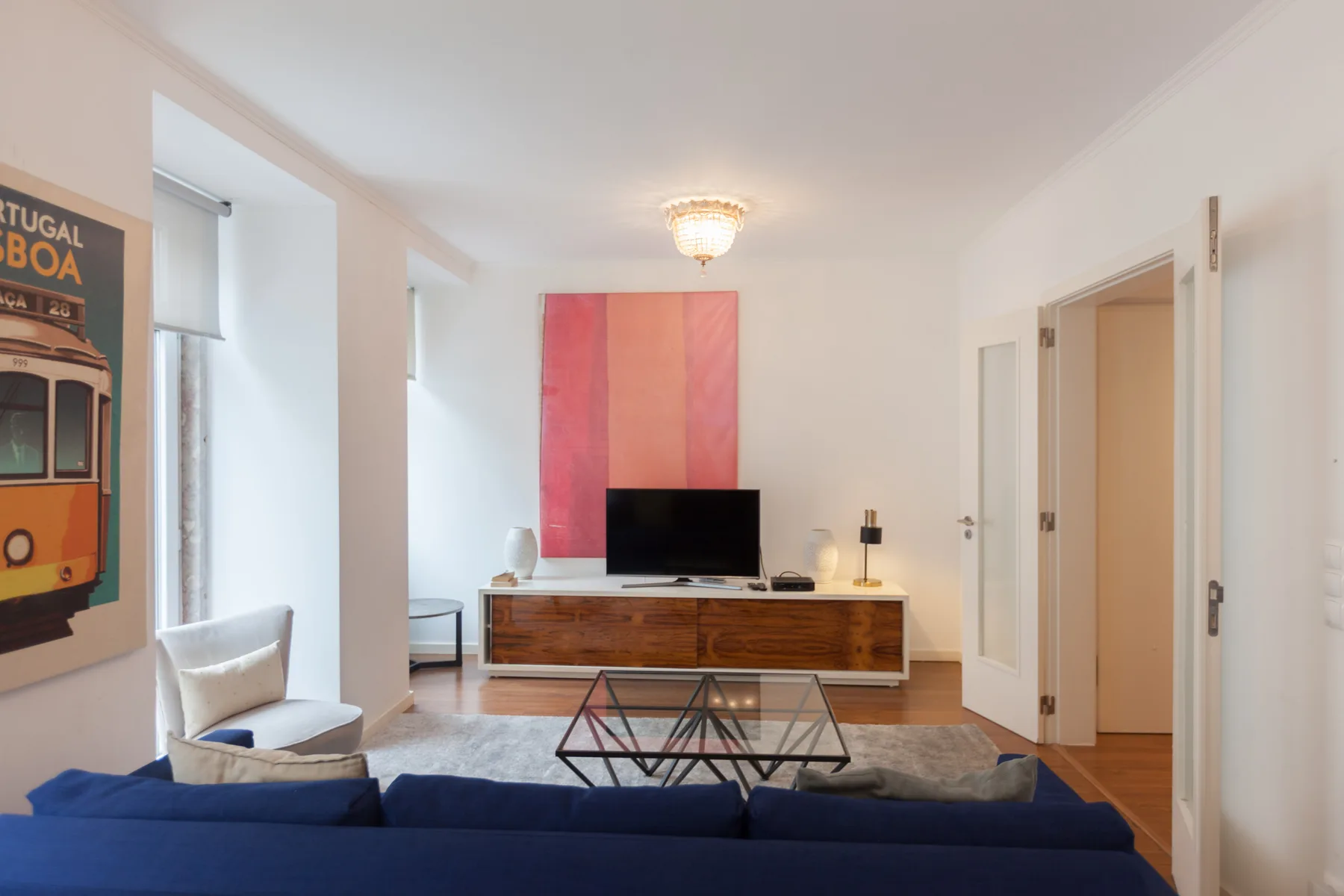 A living room with blue seating, a television, and a glass coffee table.