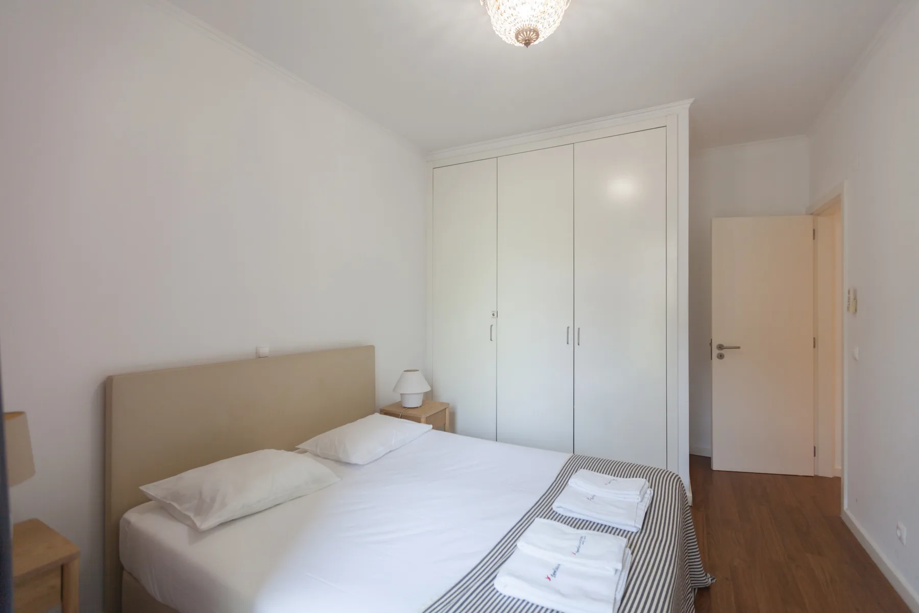 A bedroom with a bed, white bedding, and a built-in wardrobe.