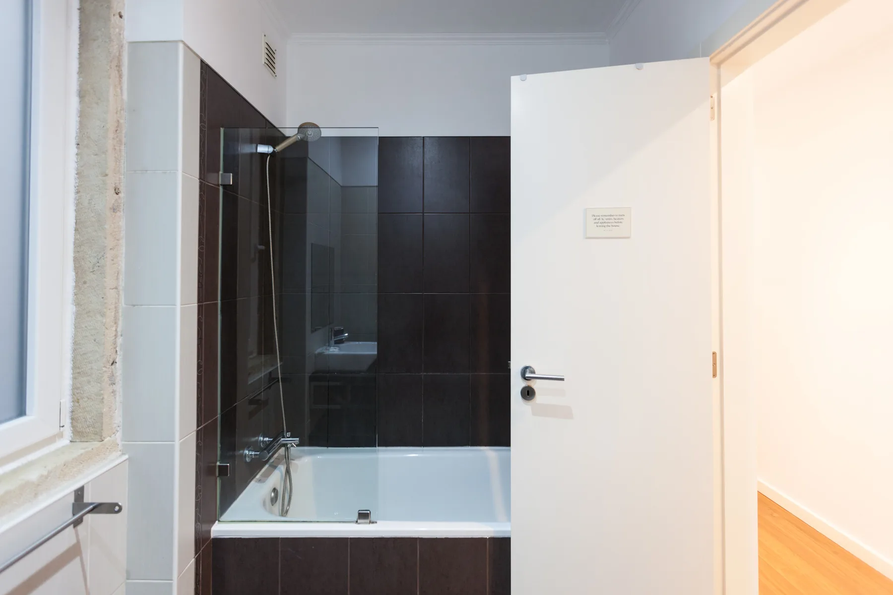 A bathroom with a bathtub and dark tiled walls.