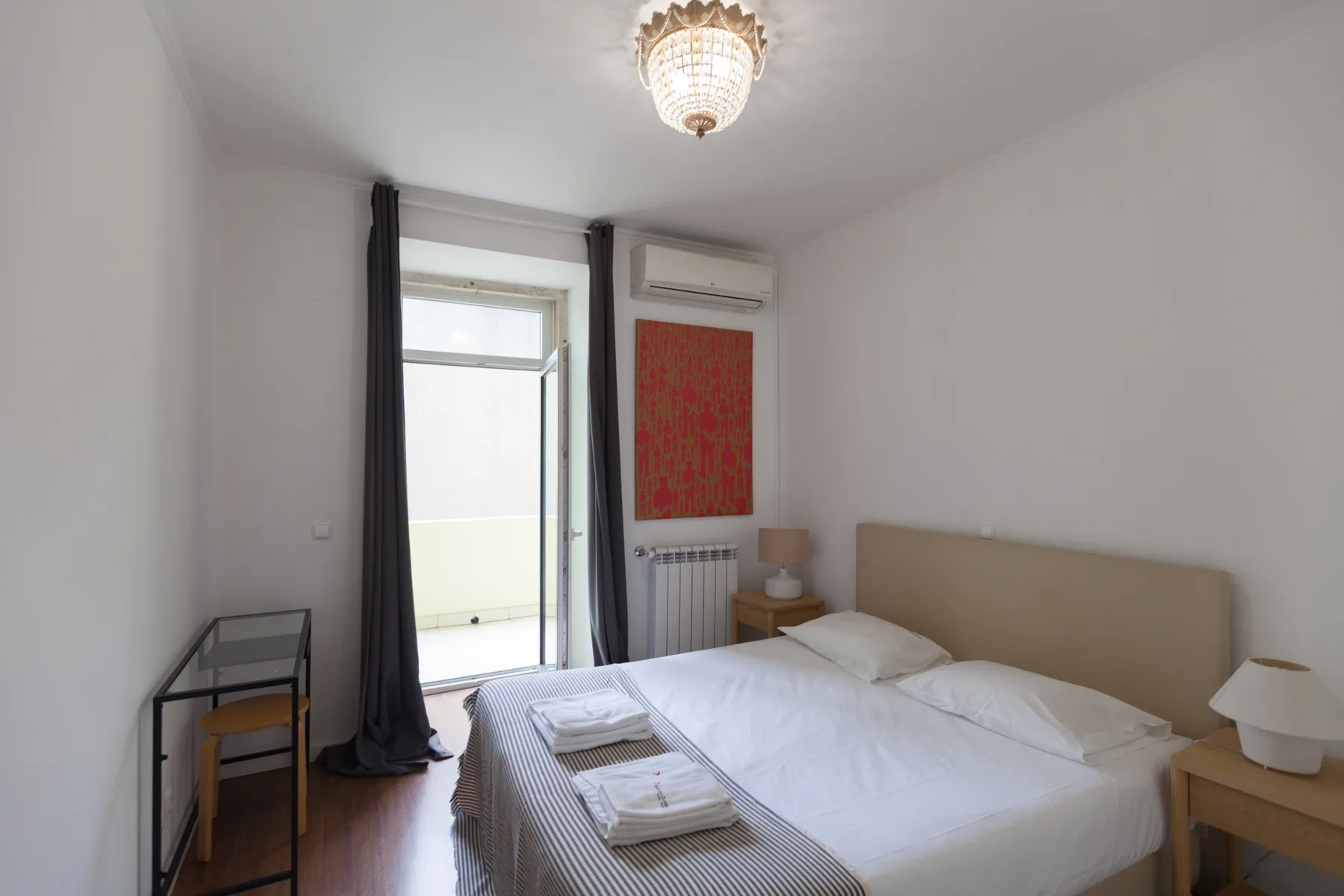 A bedroom with a bed, bedside tables, and a tall window.