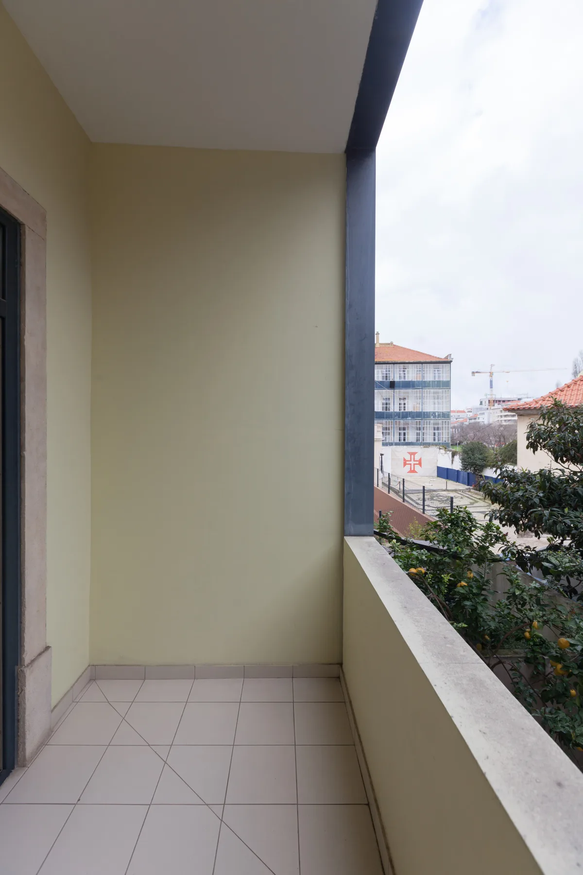 A covered balcony with a tiled floor and a view of nearby buildings.
