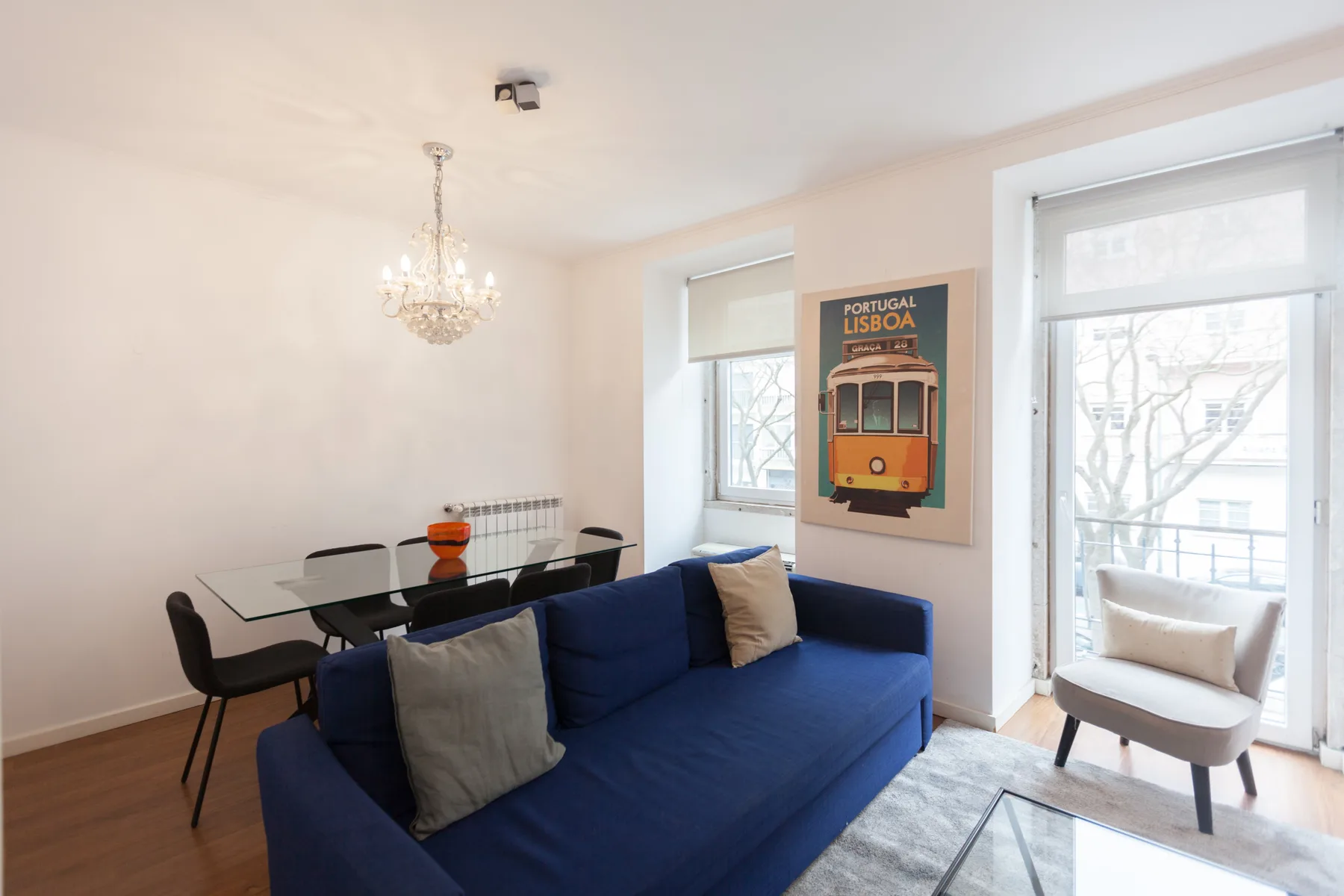 A bright living and dining area with blue seating and a glass dining table.