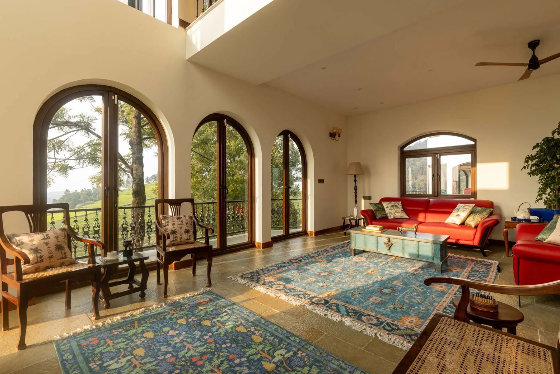 A spacious living room with arched windows, seating, and patterned rugs.