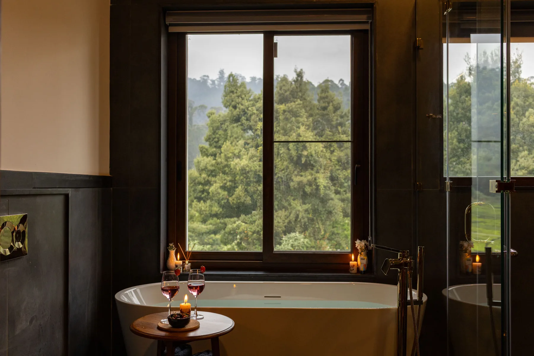 Un baño con una bañera junto a una ventana grande con vista a los árboles.