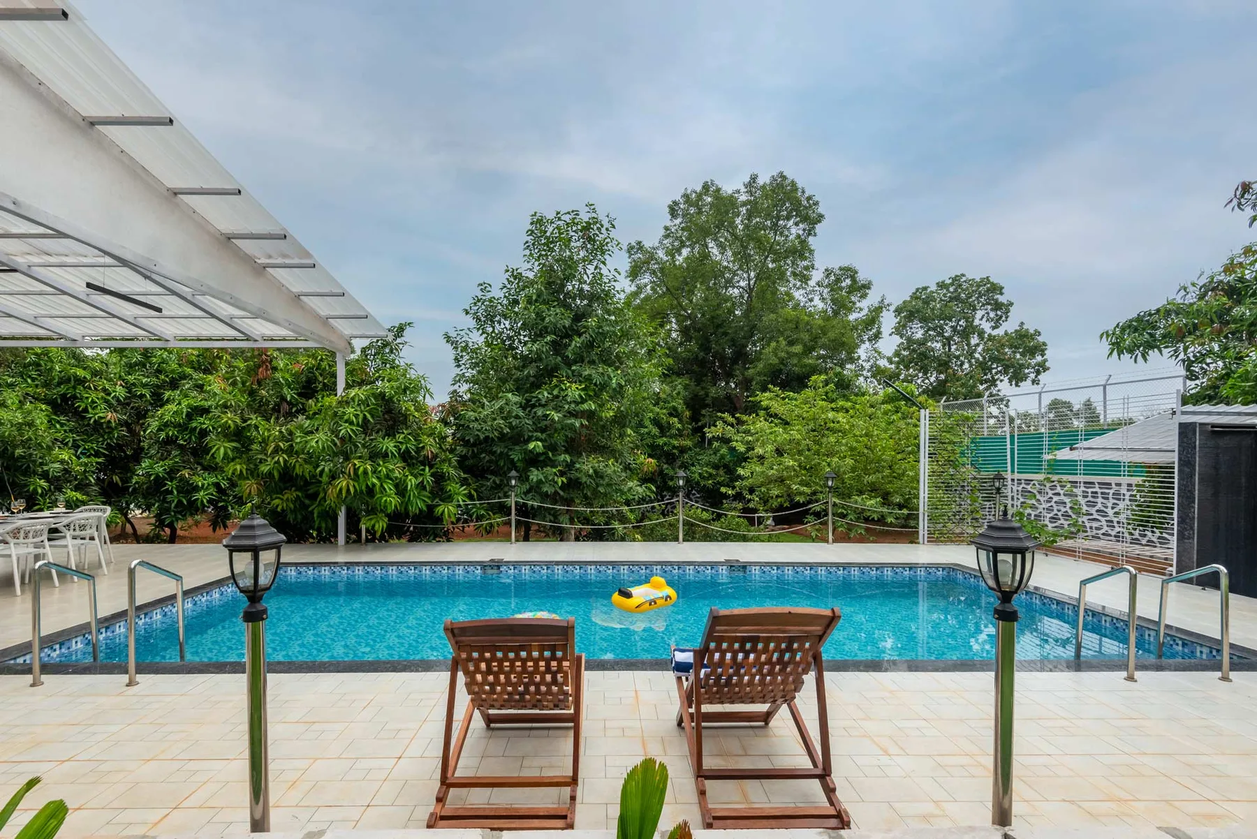 Una piscina al aire libre tiene asientos junto a la terraza de baldosas.