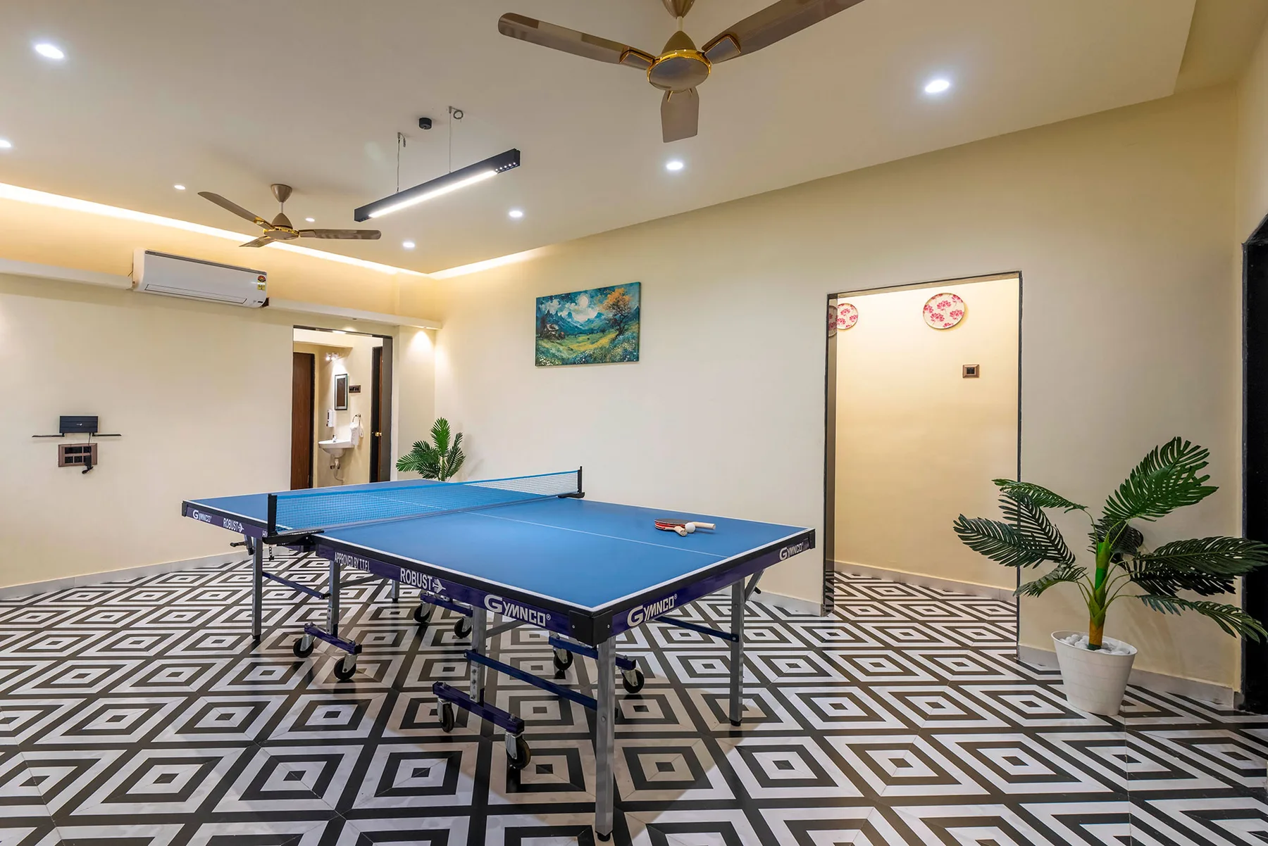 Una sala de juegos con una mesa de ping-pong azul y piso estampado.