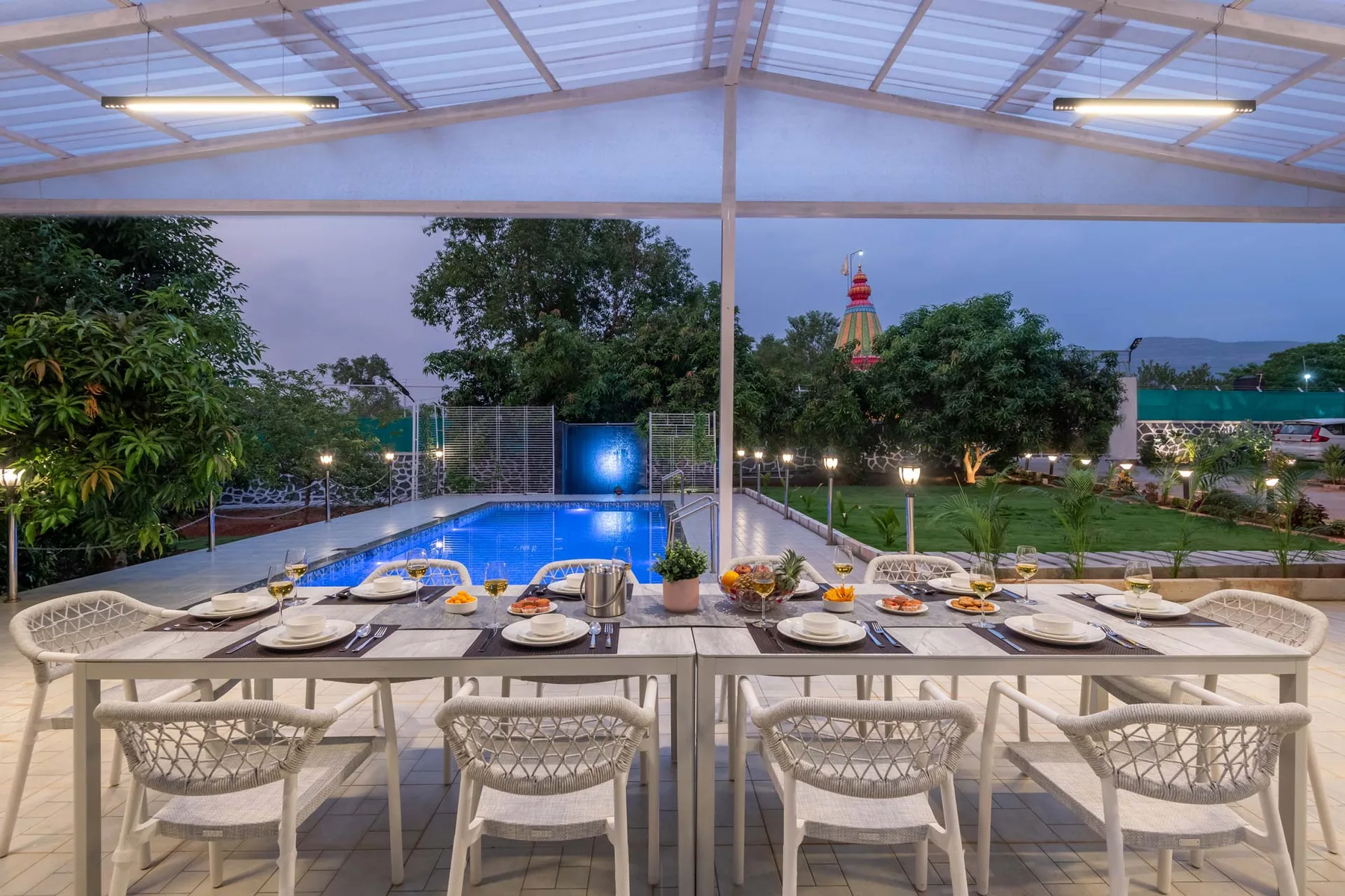Una zona cubierta para comer al aire libre da a una piscina y jardines.