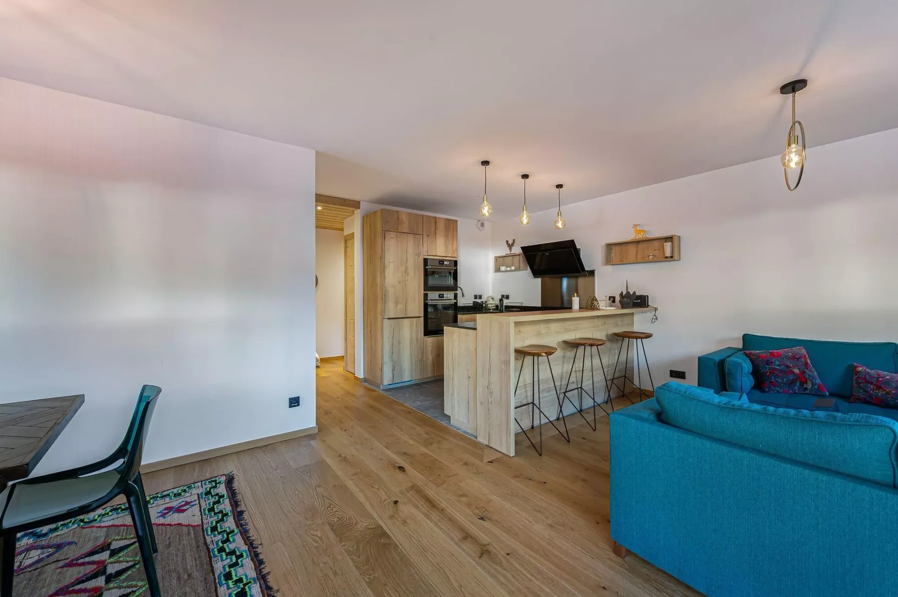 Una cocina y sala de estar de planta abierta, con una barra y asientos azules.