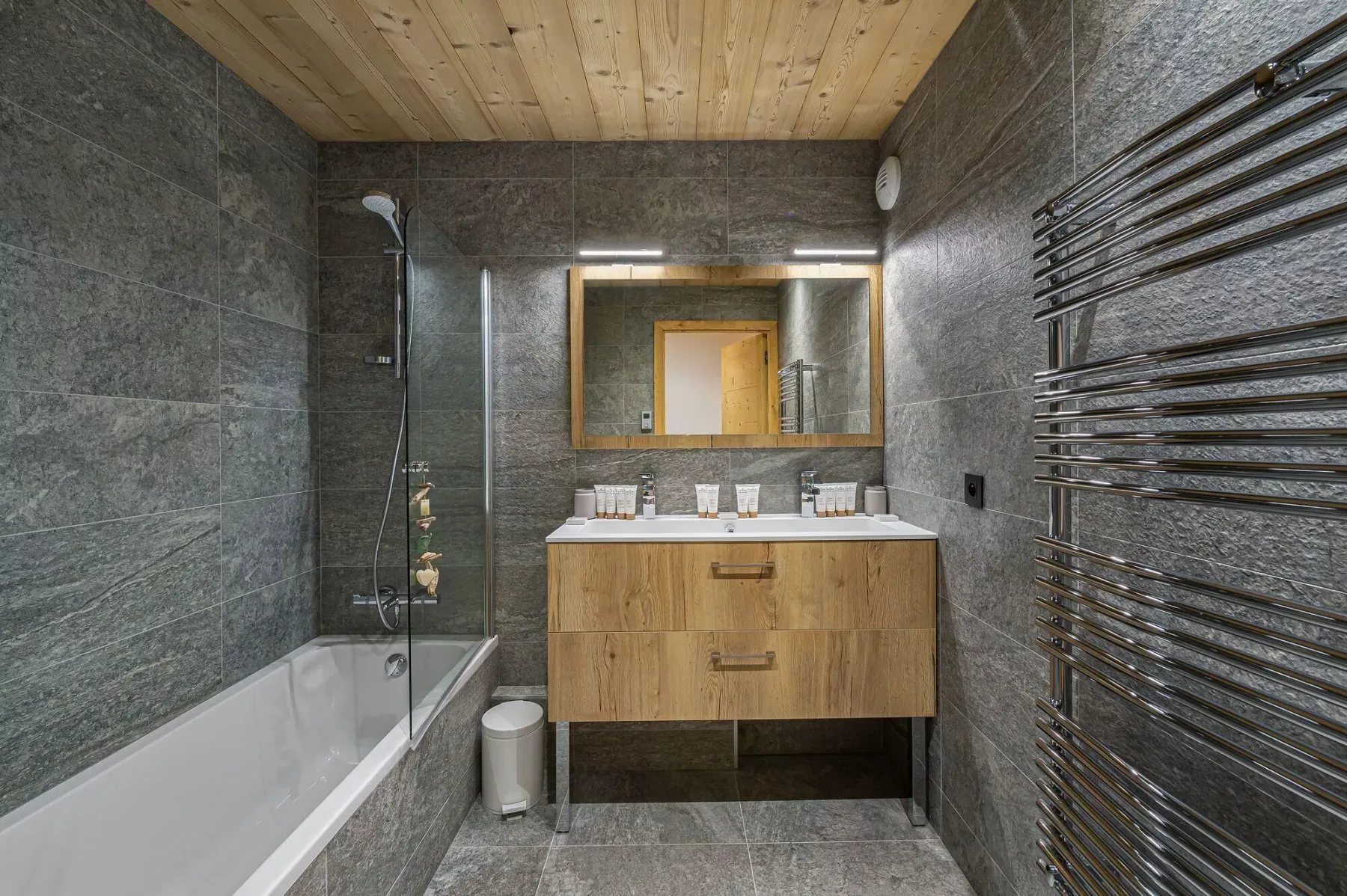 Un baño con bañera, mueble de madera y un espejo amplio.