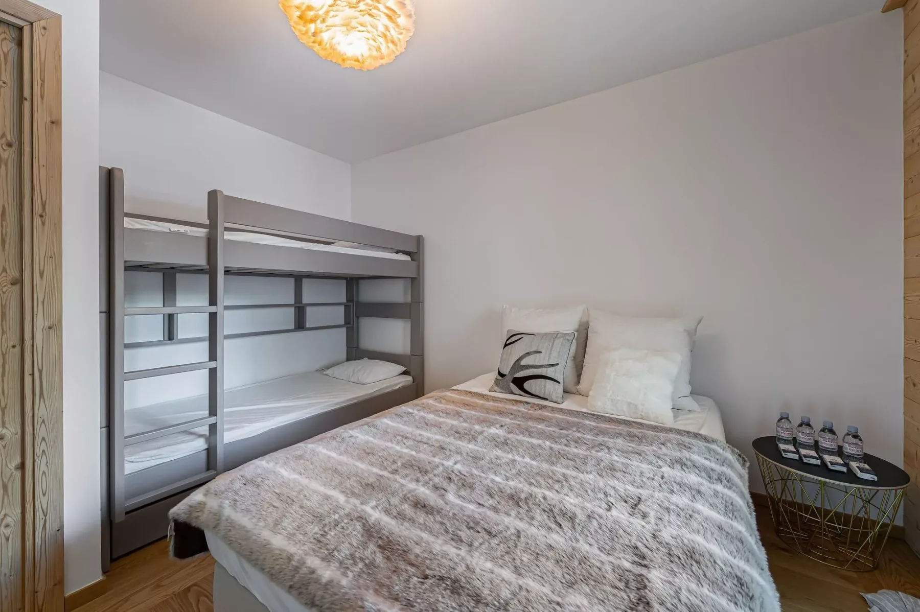 Un dormitorio con una cama doble y una litera gris junto a la pared.