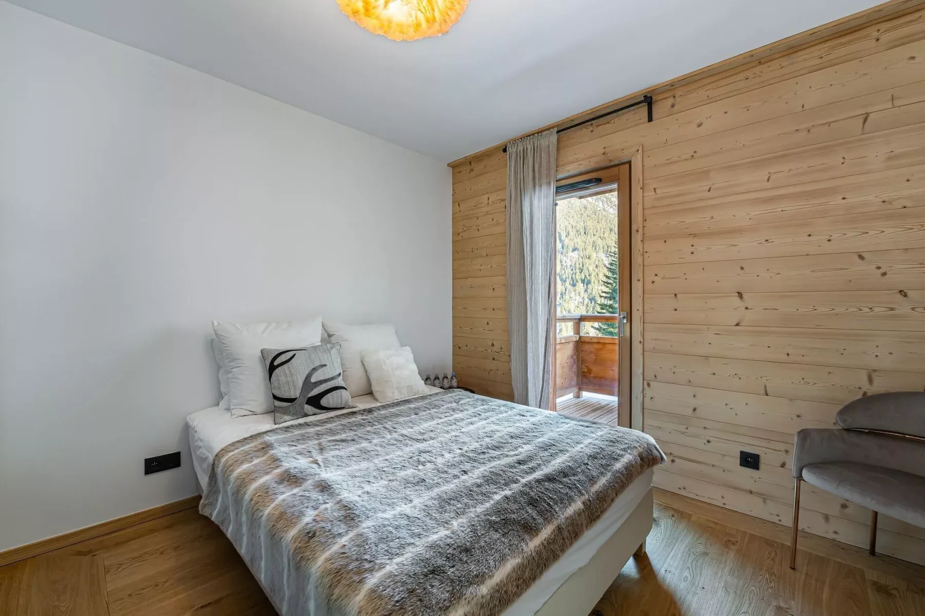 Un dormitorio con una cama junto a una pared revestida de madera y una ventana.