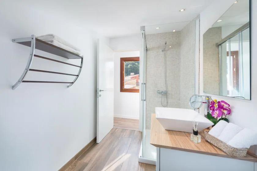 A bright bathroom with a glass shower, vanity, and basin.