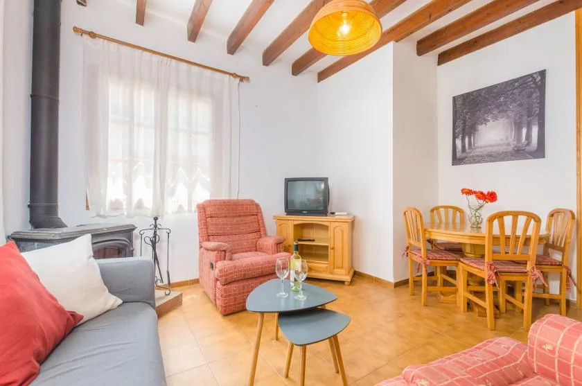 A living and dining area with seating, a wooden table, and exposed ceiling beams.