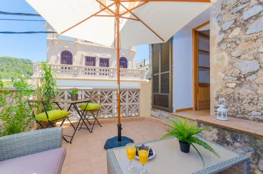 Un patio al aire libre con asientos, una sombrilla grande y plantas en macetas.
