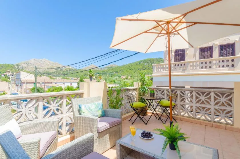 A rooftop terrace with outdoor seating beneath a large sun umbrella.