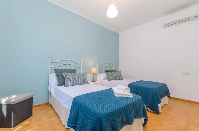A bedroom with two beds covered in blue bedding.