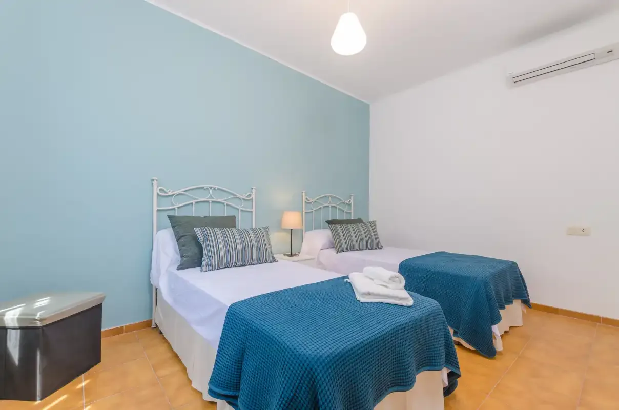 A bedroom with twin beds dressed in white linens and blue covers.