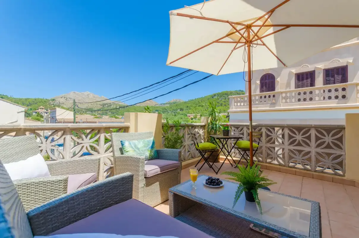 Outdoor terrace seating beneath a large umbrella, with hills visible in the distance.